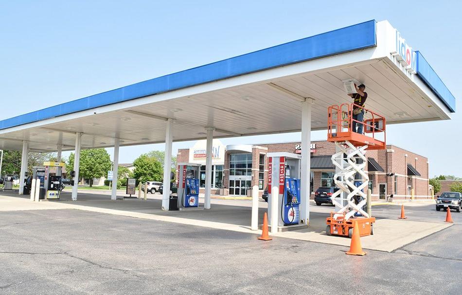 man in a scissor lift at a gas station installing lighting in the canopy covering gas pumps